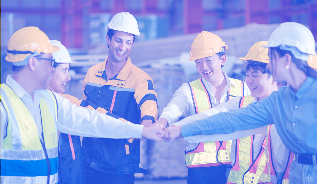 Trabajadores en equipo celebrando con un saludo de puños en una obra.