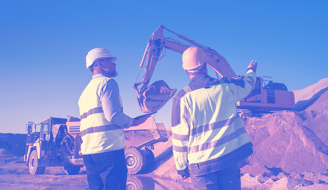 Supervisores de seguridad revisando operación de maquinaria pesada en una obra.